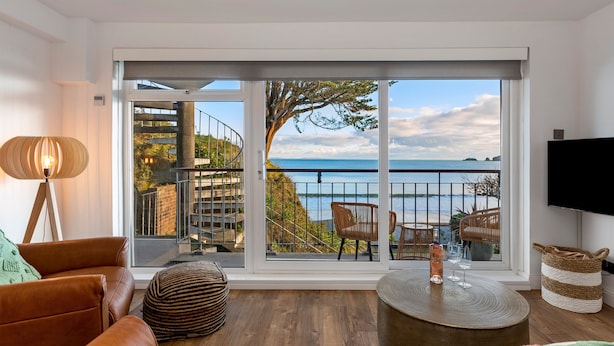A modern living room with a large sliding glass door leading to a balcony with a view of the sea. - Beach Retreat - Sea Views Parking Beach Access (Saundersfoot)