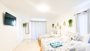 A bedroom with two beds, a TV, a mirror, and a window with curtains. - Cozy & Comfortable Studio in brilliant Puerto Plata - Beach & Pool Access (Puerto Plata)