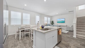 Una cocina moderna con armarios blancos, encimera de granito y lavavajillas integrado.