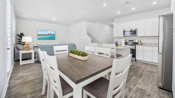 Una cocina moderna con armarios blancos, microondas integrado y refrigerador de acero inoxidable.