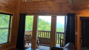 A wooden cabin with a balcony, large windows, and a view of greenery. - Epic Mountain Views above Dollywood HotTub&ResPool (Sevierville)