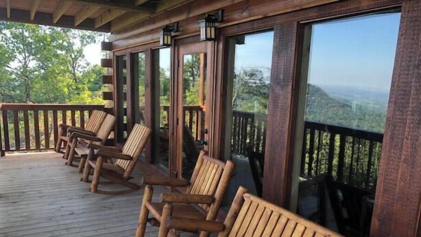A wooden deck with several wooden chairs and large windows offering a view of the landscape. - Epic Mountain Views above Dollywood HotTub&ResPool (Sevierville)