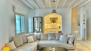 A modern living room with a sectional sofa, a round coffee table, and a kitchen visible through an archway.