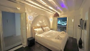 A bedroom with a bed, a nightstand, a TV, and a balcony with a city view.