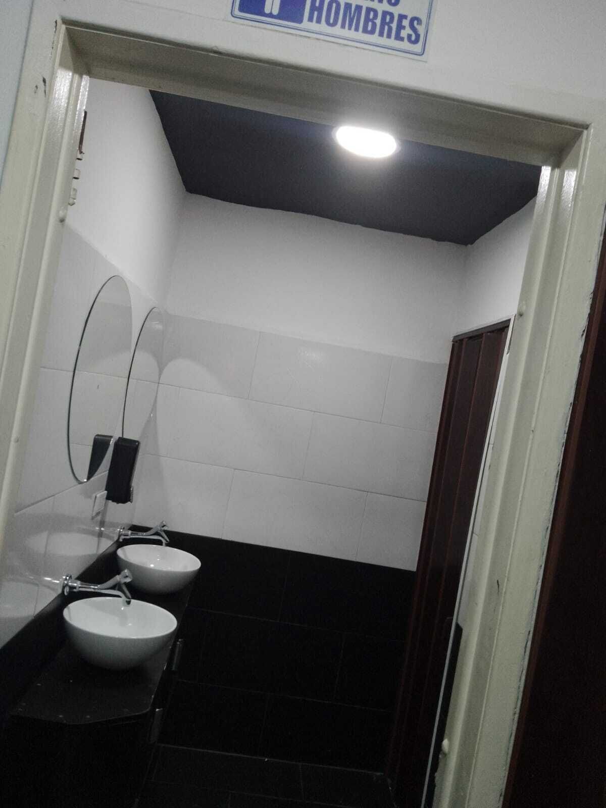 A men's restroom with two sinks, a mirror, and a sign indicating the gender.