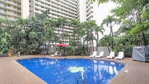 A swimming pool with lounge chairs and palm trees. - Waikiki Marina Ocean View Studio w/ Parking (Honolulu)