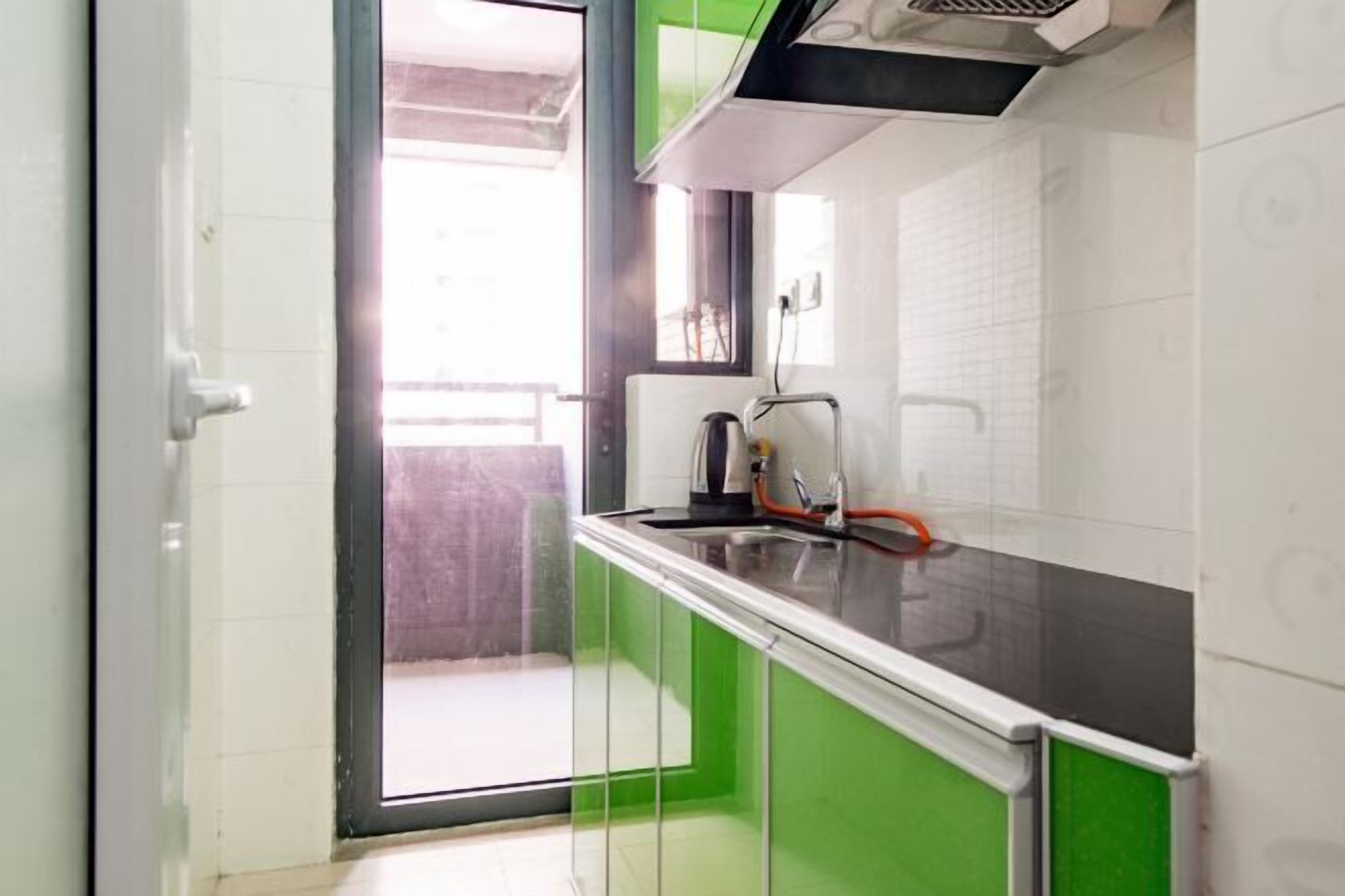 A kitchen with a black countertop, green cabinets, and a window.