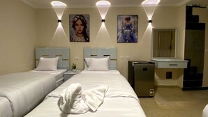 A hotel room with two beds, a minibar, a desk, and a mirror. - Sky light hotel (Cairo)