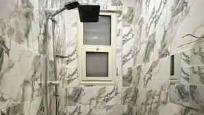 A bathroom with marble walls, a toilet, a sink, and a shower with a glass enclosure. - Sky light hotel (Cairo)