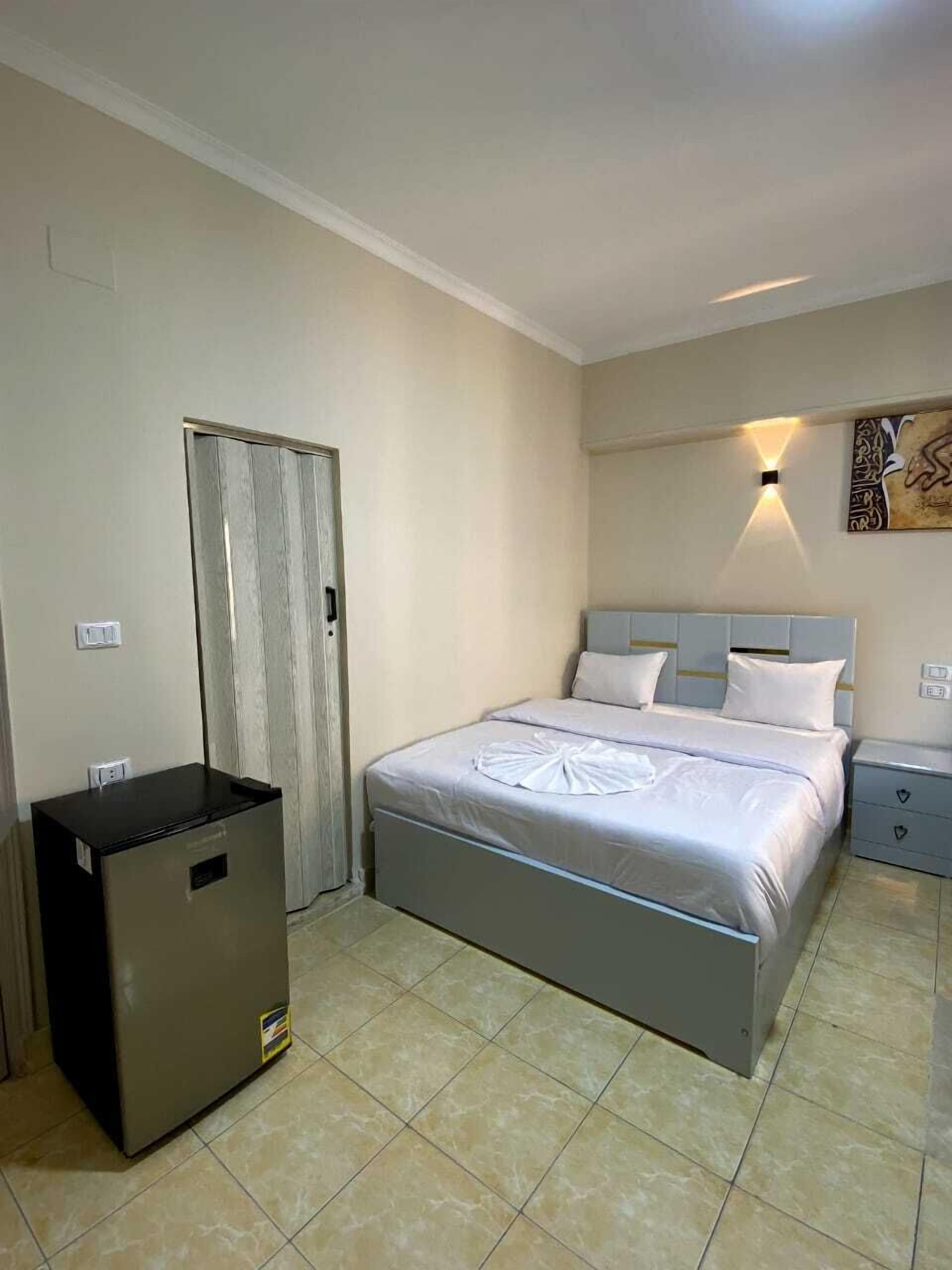 Une chambre d’hôtel comprenant un lit, une table de chevet, une armoire et un petit réfrigérateur.