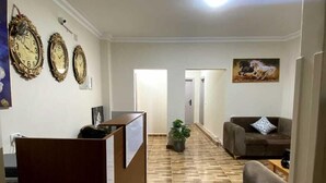 A hallway with a reception desk, a brown sofa, and a painting of a horse. - Sky light hotel (Cairo)