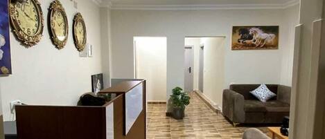 A hallway with a reception desk, a brown sofa, and a painting of a horse.