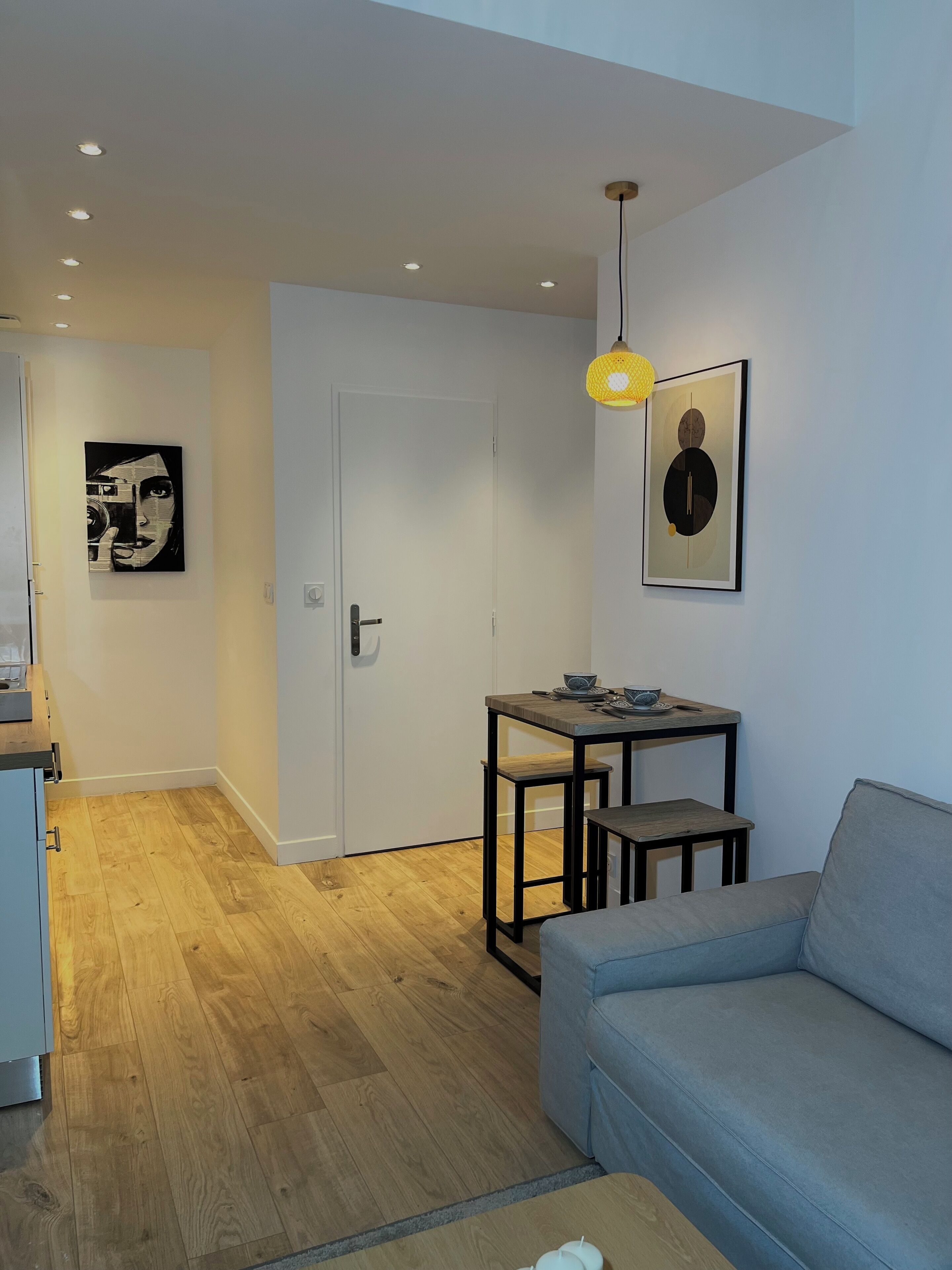 A modern living room with a sofa, a small table, and two wall-mounted artworks.