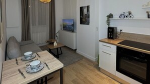 A modern kitchen with a dining area, wooden flooring, and pendant lighting. - Cosy apartment (Tarare)