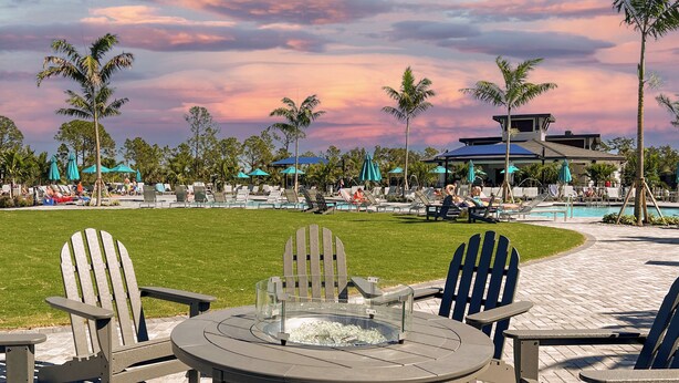A poolside area with Adirondack chairs, a glass-top table, and a fire pit.