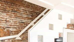 A modern living room with a white sofa, a wooden coffee table, and a brick wall. - Rhythm&Views- Hillside home in Mount Adams with Hot Tub and River Views (Cincinnati)
