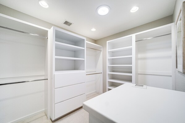 A walk-in closet with open doors, revealing multiple shelves and drawers.