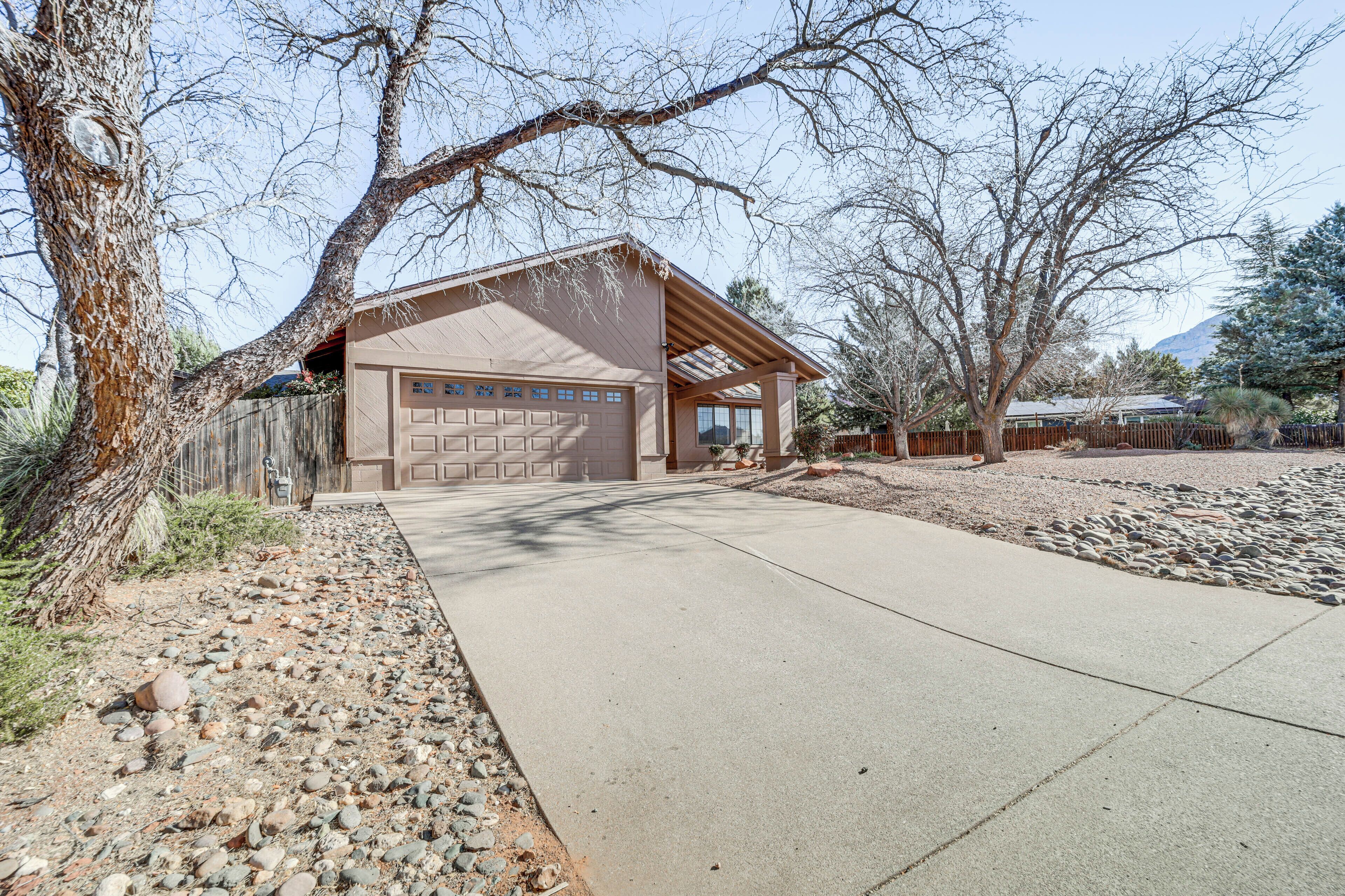 A single-story house with a garage, a paved driveway, and a landscaped area with rocks and sparse vegetation.