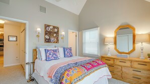Une chambre à coucher avec un lit, une commode et un grand miroir.