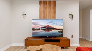 A modern living room with a flat-screen TV mounted on a wooden entertainment unit, a wooden slat wall design, and two wall-mounted planters.