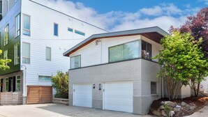 A modern two-story residential building with a garage, a brick facade, and a sloped roof.