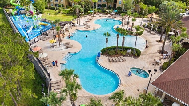 A large outdoor swimming pool with multiple lanes, surrounded by palm trees and lounge chairs. - TOP-RATED Windsor Hills Resort Villa ♥ THEATER/GAME ROOM, Pool ♥ 4 Mi to Disney (Kissimmee)