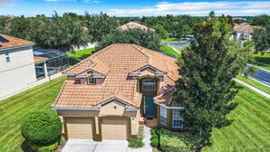 A single-story house with a tiled roof, a front garage, and a well-maintained lawn. - TOP-RATED Windsor Hills Resort Villa ♥ THEATER/GAME ROOM, Pool ♥ 4 Mi to Disney (Kissimmee)