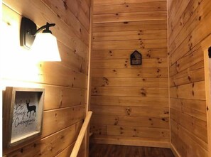 Cozy cabin interior with a sloped ceiling, featuring a framed sign and a rustic birdhouse.