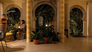 A lobby with a central archway, potted plants, and a seating area. - O Portalzinho (Paraty)