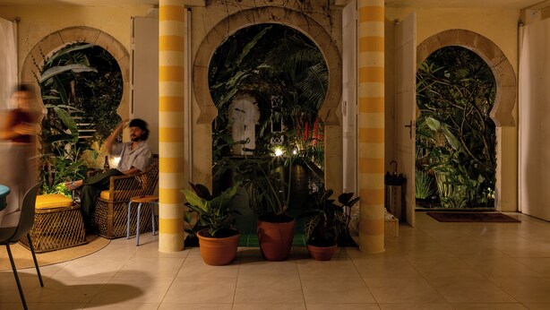 A lobby with a central archway, potted plants, and a seating area. - O Portalzinho (Paraty)