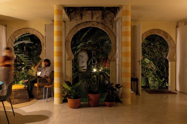 A lobby with a central archway, potted plants, and a seating area. - O Portalzinho (Paraty)