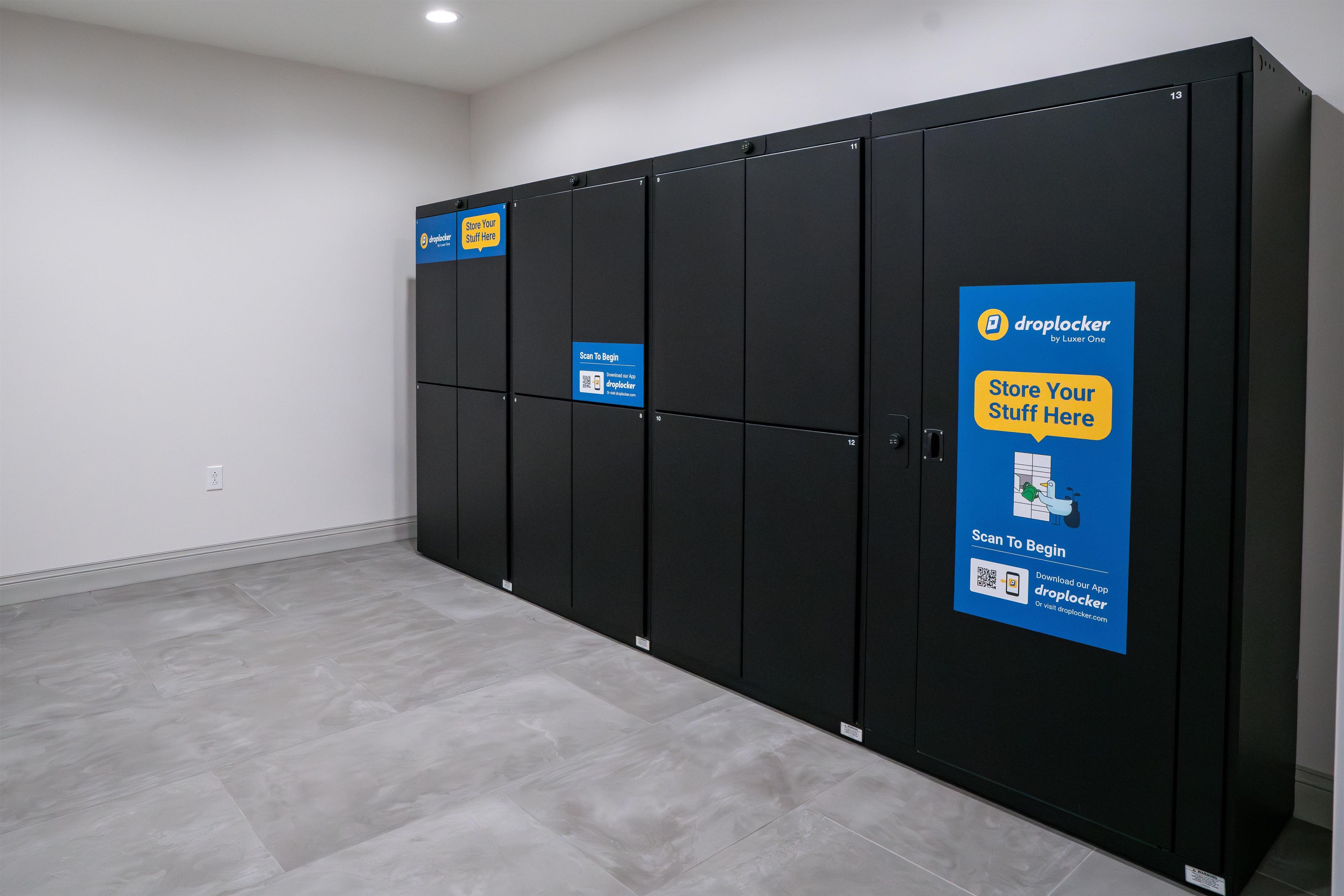 A row of black lockers with blue signage advertising a mobile app for storing items.