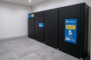 A row of black lockers with blue signage advertising a mobile app for storing items.