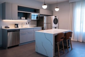 A modern kitchen with a central island, stainless steel appliances, and pendant lighting.