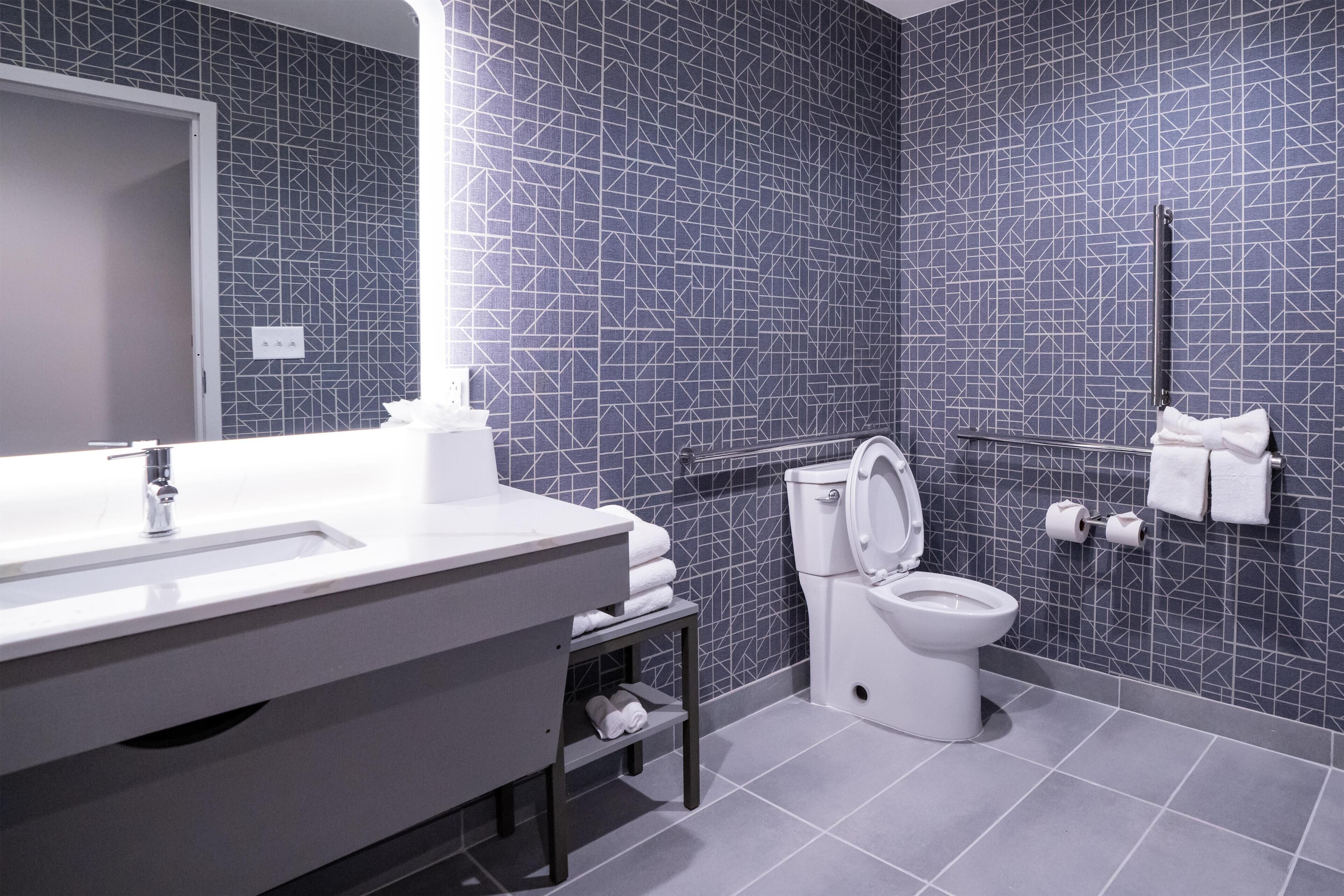 A modern bathroom with a geometric tile backsplash, a white sink, and a toilet.