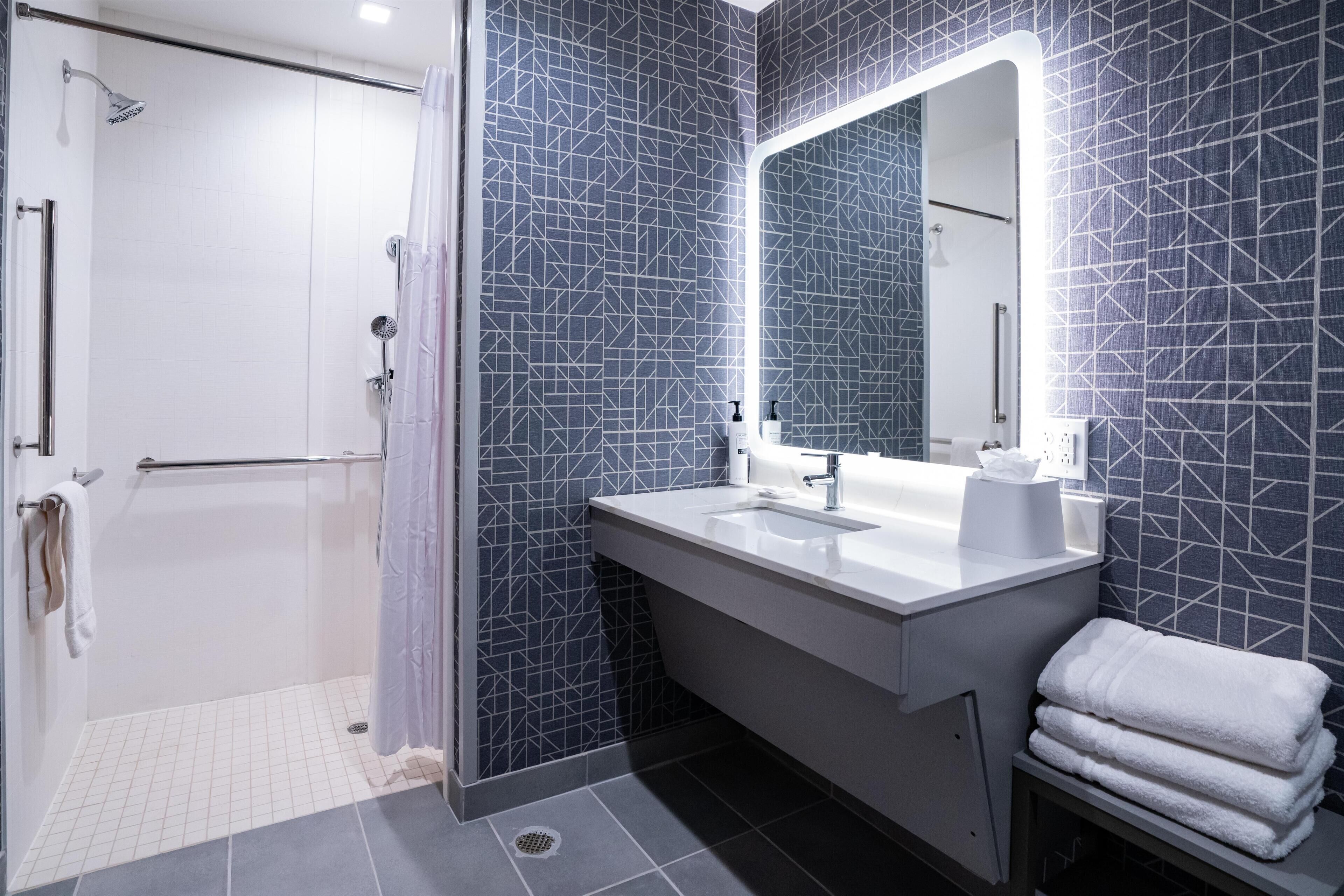 A modern bathroom with a shower, a sink, and a mirror.
