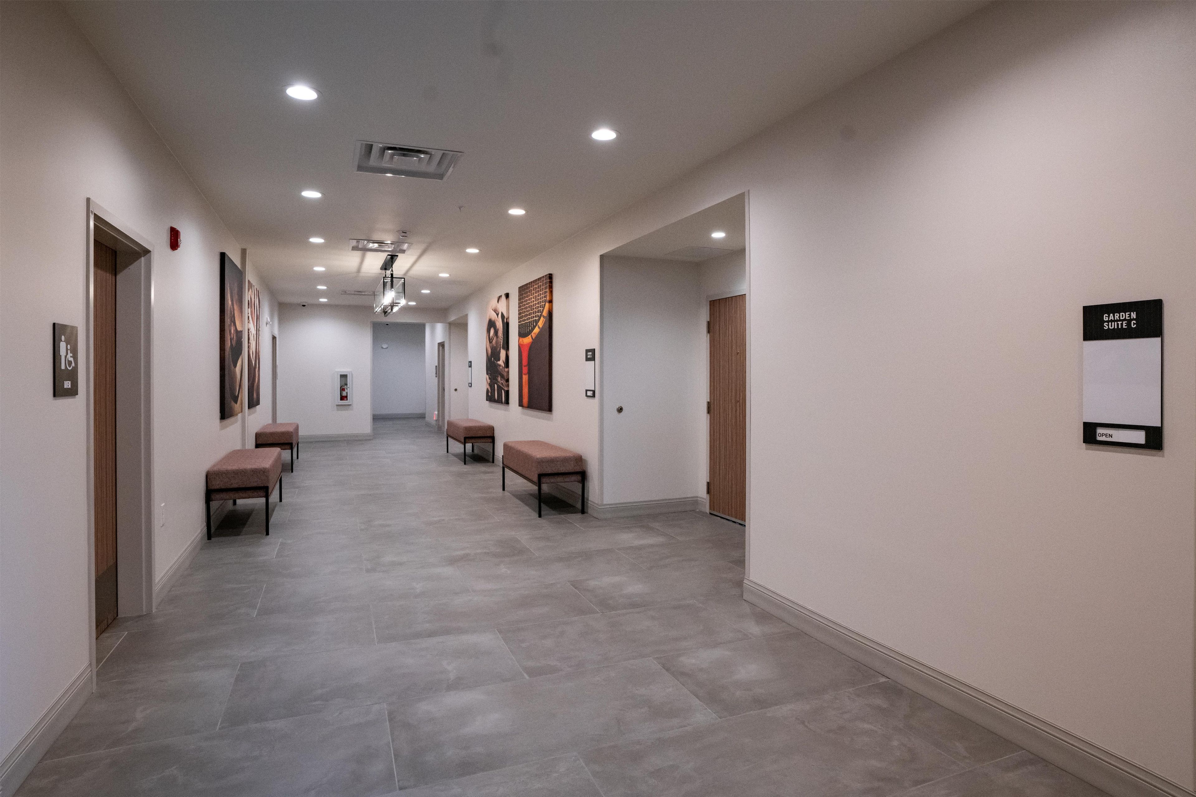 A hallway with benches, a fire alarm, and a sign indicating 'Garden Suite C'.