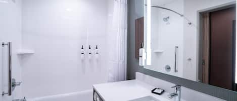 A modern bathroom with a bathtub, a large mirror, and a vanity with a sink.