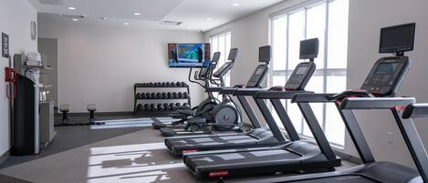 A gym with treadmills, dumbbells, and exercise equipment.