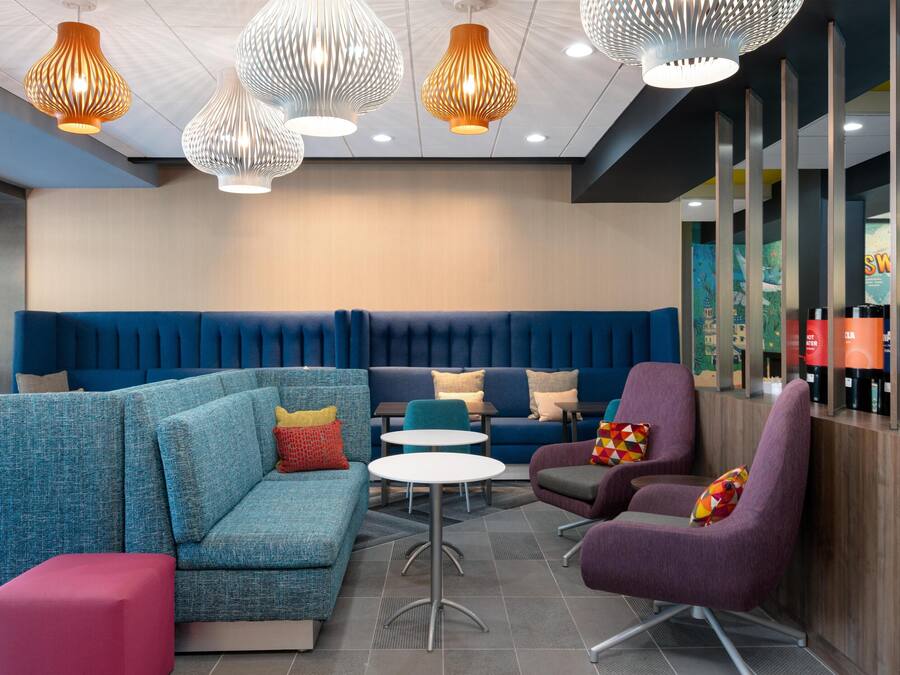 A modern lounge area with blue seating, white tables, and decorative pendant lights.