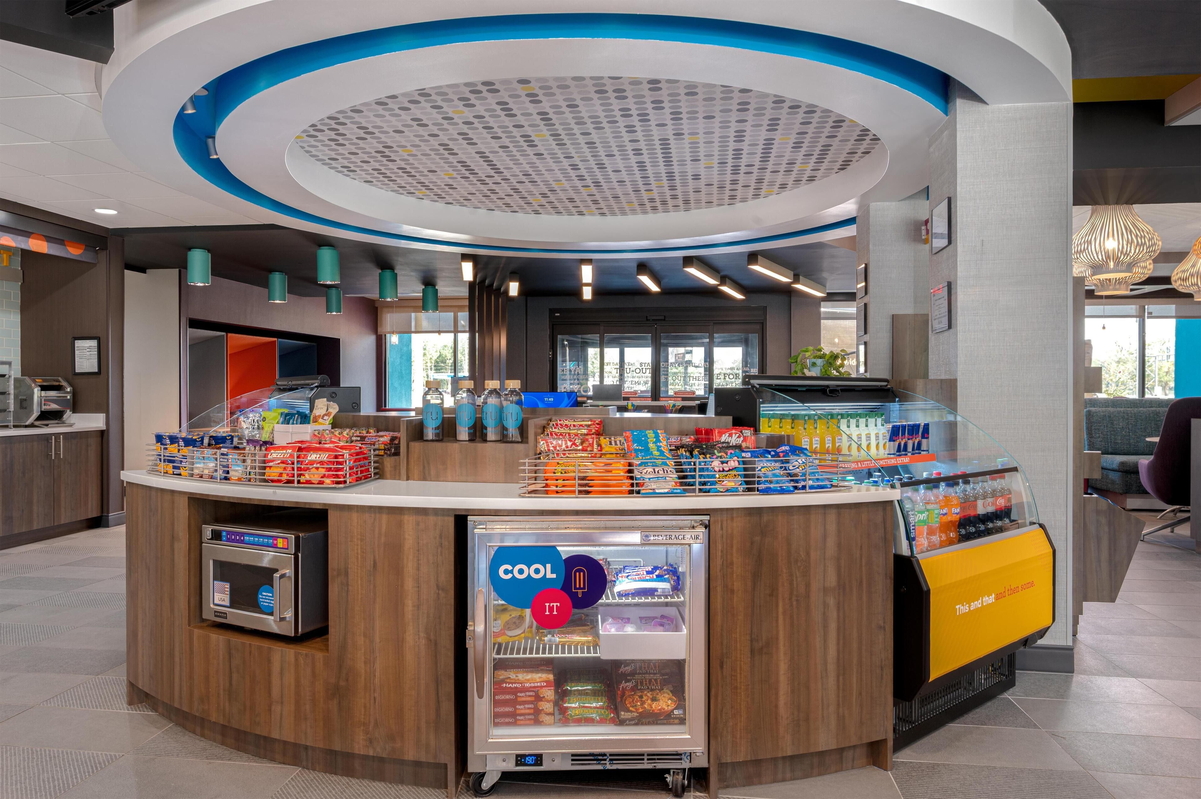 A modern self-service kiosk with a variety of snacks and beverages, a refrigerated section, and a digital payment terminal.