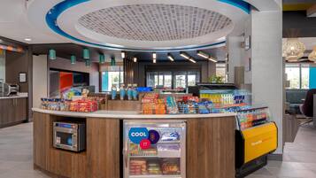 A modern self-service kiosk with a variety of snacks and beverages, a refrigerated section, and a digital payment terminal.