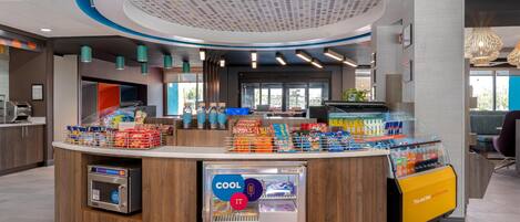 A modern self-service kiosk with a variety of snacks and beverages, a refrigerated section, and a digital payment terminal.