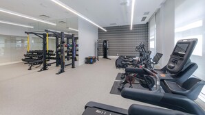 Un gimnasio moderno con equipo de ejercicio, espejos y un revestimiento de pared estampado.