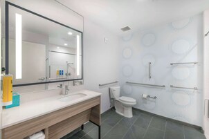 Un baño moderno con un espejo grande, lavamanos blanco y retrete.