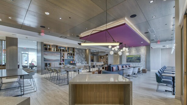 Un interior moderno con una isla central, zonas de estar y una cocina al fondo.