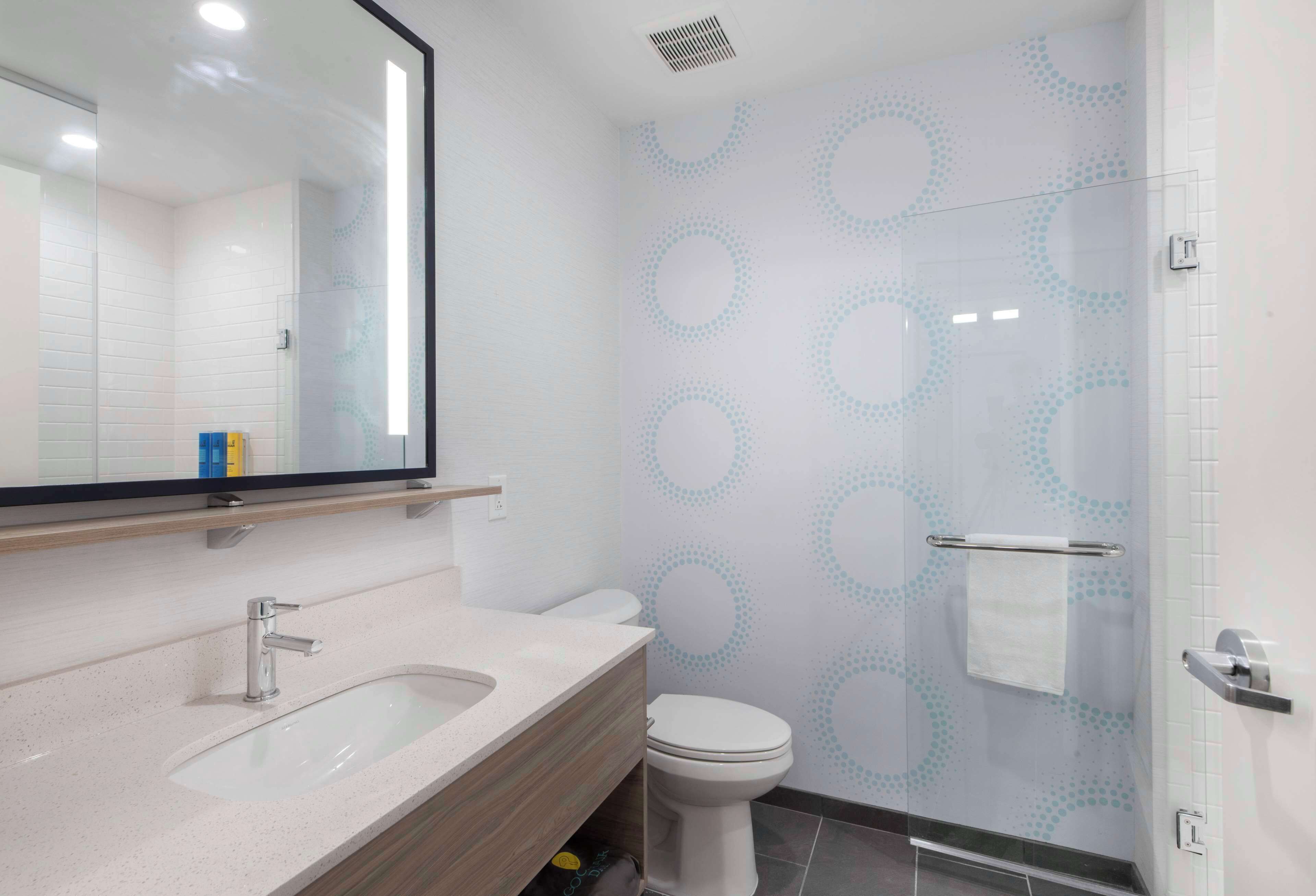 Un bagno moderno con lavandino bianco, uno specchio e un water.