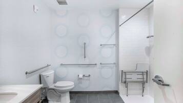 Een moderne badkamer met toilet, bidet en douche, voorzien van handgrepen en een handrail.