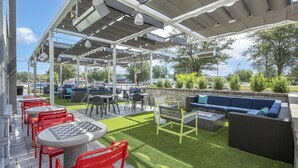 Un área de patio al aire libre con mesas, sillas, un sofá y un pozo de fuego.