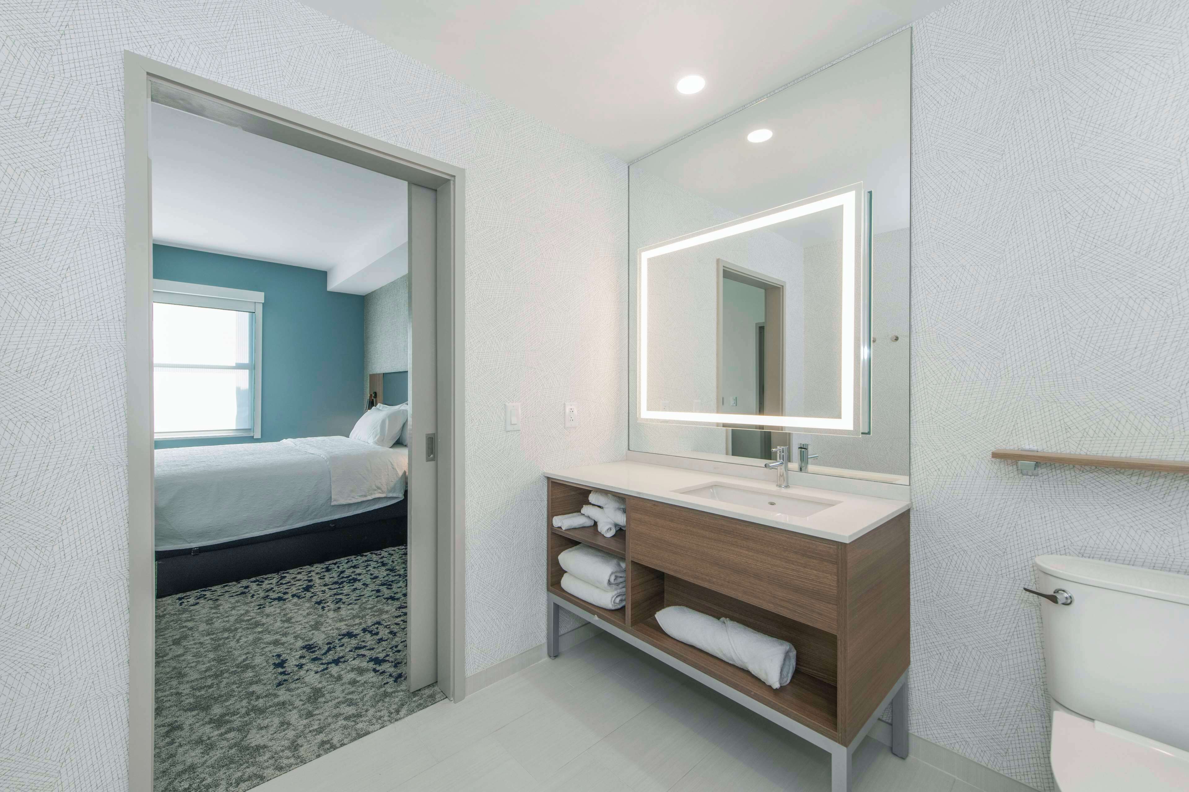 Une salle de bain moderne avec un grand miroir, un lavabo blanc et des toilettes.